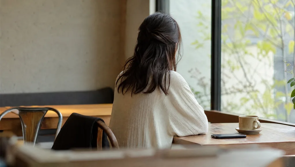 スマホを置いてカフェで一息つく女性の写真風イメージ